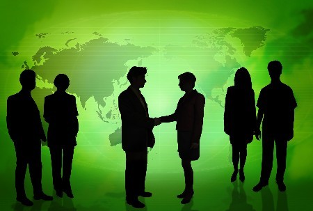 Silhouettes of business people in front of a green world map